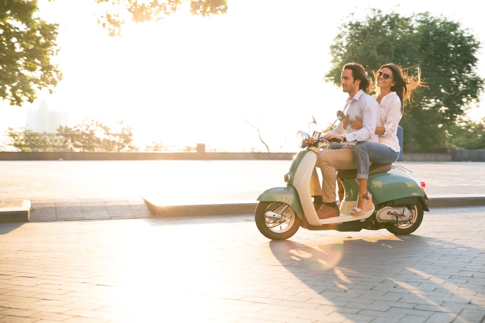 Happy young couple riding a scooter and having fun. Sun is shining in the morning-1